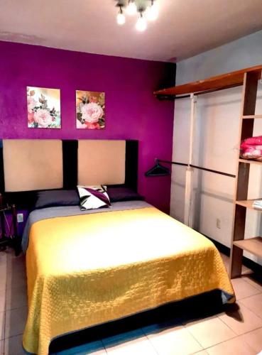 a bedroom with a yellow bed with purple walls at La Terraza del Pochote in Oaxaca City