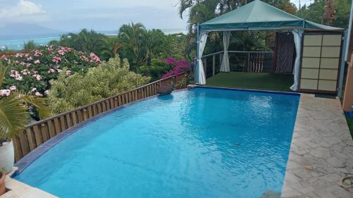 a large blue swimming pool with a gazebo at Maeva Sunset View in Punaauia