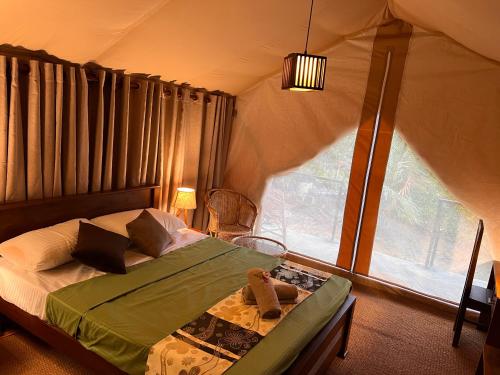a bedroom with a bed in a tent with a window at AT ONE - with Nature Glamping Resort in Rekawa
