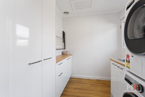 a laundry room with white cabinets and a washer and dryer at Renovated Lux Property in Quiet Estate in Cowes