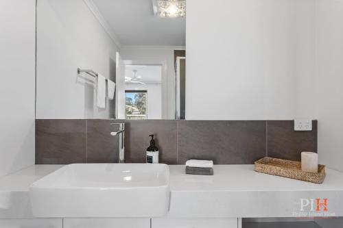 a white bathroom with a sink and a mirror at Renovated Lux Property in Quiet Estate in Cowes