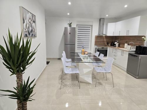una cucina con tavolo di vetro e sedie bianche di Maison Challans a Challans