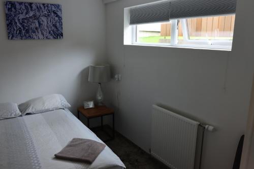 a small bedroom with a bed and a window at Höfn Hostel in Höfn