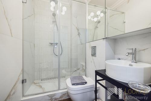 a bathroom with a shower and a toilet and a sink at Polonia Residence Glamour by LookAp in Łódź