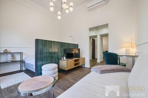 a living room with a couch and a tv at Polonia Residence Glamour by LookAp in Łódź