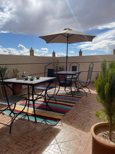 a patio with two tables and an umbrella at Dar Mgouna Roses in Kalaat MGouna
