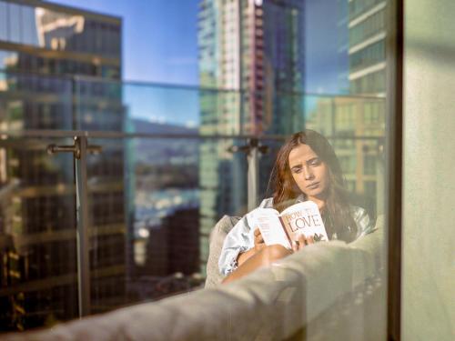 a woman sitting in a chair reading a book at Paradox Vancouver in Vancouver