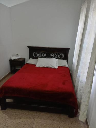 a bedroom with a red bed with a red blanket at Hotel Esmeralda Duitama in Duitama