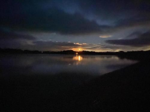 a misty lake with the sun setting in the background at Autumn Special Offer - Secluded Luxury Cabins with stream, stargazing, walks and nature - Fell Farm Hideaway in Colwell