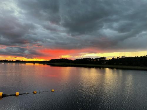 a sunset on a lake with ducks in the water at Autumn Special Offer - Secluded Luxury Cabins with stream, stargazing, walks and nature - Fell Farm Hideaway in Colwell