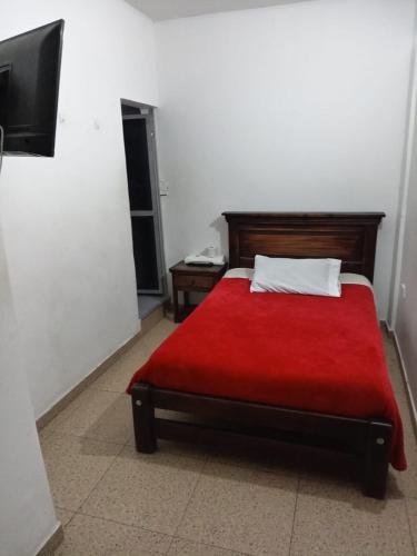 a bedroom with a bed with a red blanket at Hotel Esmeralda Duitama in Duitama