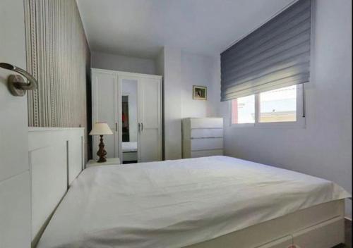 a bedroom with a large white bed with a window at 5 minutos hacia el mar in El Campello