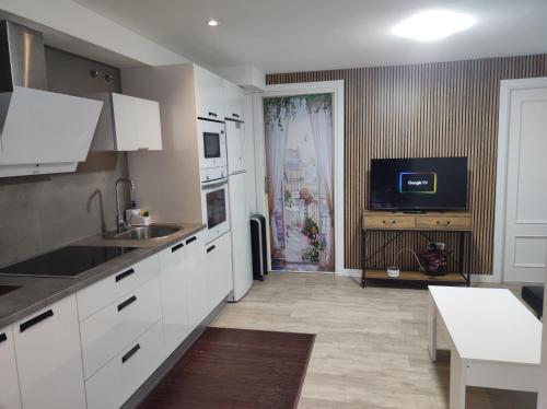 a kitchen with white cabinets and a tv on the wall at el rincón de florida in Vigo