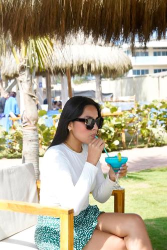 a woman sitting in a chair with a drink at Hotel Presidente Beach Playas in Playas