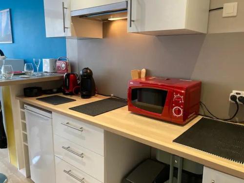 un four micro-ondes rouge installé au-dessus d'un comptoir de cuisine dans l'établissement Studio en résidence, aux Trois-Epis, à Turckheim