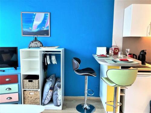 une cuisine avec un mur bleu et un tabouret de bar dans l'établissement Studio en résidence, aux Trois-Epis, à Turckheim