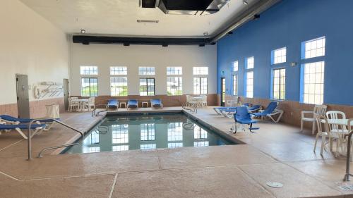 a pool in a room with blue chairs and tables at Comfort Inn in Santa Fe