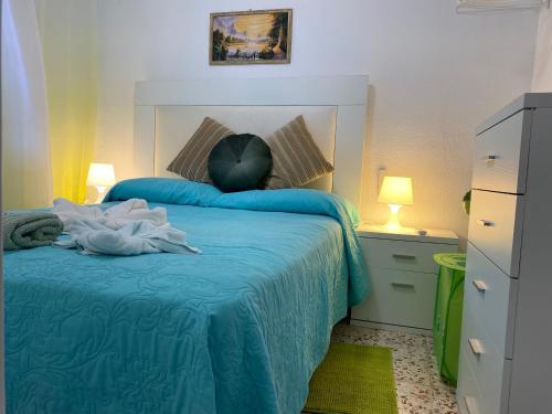 - une chambre avec un lit avec une couverture bleue et 2 lampes dans l'établissement La casa amarilla de Luis y Eileen, à La Vila Joiosa