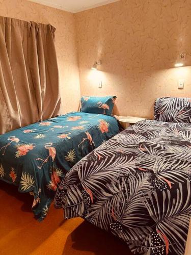 deux lits côte à côte dans une chambre dans l'établissement Ōmāpere Bach, à Omapere