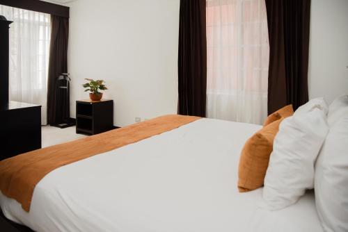a bedroom with a large bed with white sheets and pillows at Casa Conde Hotel & Apartamentos in San José