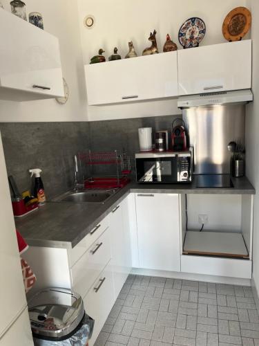 une cuisine avec des armoires blanches et un micro-ondes dans l'établissement Grand studio à 2mn du port et 40mn des pistes de ski, à Nice