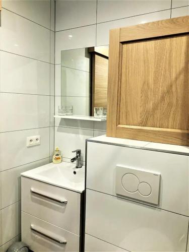 - une cuisine blanche avec un évier et un miroir dans l'établissement Studio en résidence, aux Trois-Epis, à Turckheim