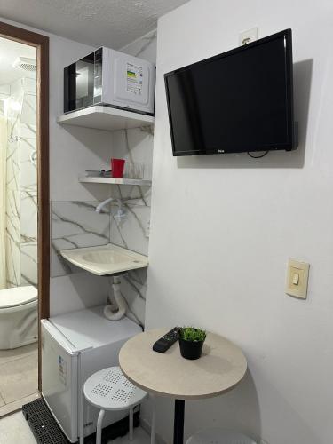 a room with a table and a tv on a wall at Studio Boa Viagem in Recife