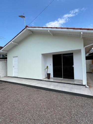 ein weißes Haus mit einer Topfpflanze davor in der Unterkunft Refúgio da Camboa - Casa Menta in Governador Celso Ramos