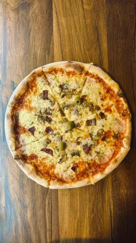 a pizza sitting on top of a wooden table at Intermezzo2 in Prijepolje