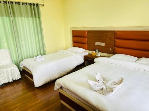 a hotel room with two beds with white sheets at Tiger Wildlife Resort in Bharatpur