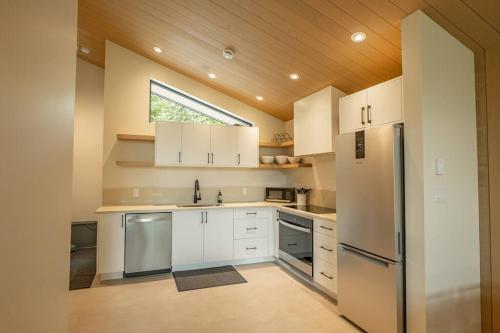 a kitchen with white cabinets and a window at Calmwater Retreat New 2 br Hot Tub in Ucluelet