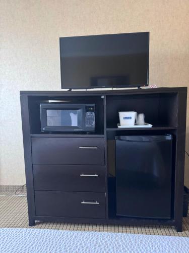 a black entertainment center with a microwave and a tv at Travelodge by Wyndham Prince Albert in Prince Albert
