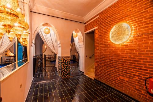 a room with a brick wall and a chandelier at Riad L'ECOLE in Marrakech