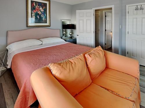a bed with an orange couch in a bedroom at Sea Chase in Topsail Beach