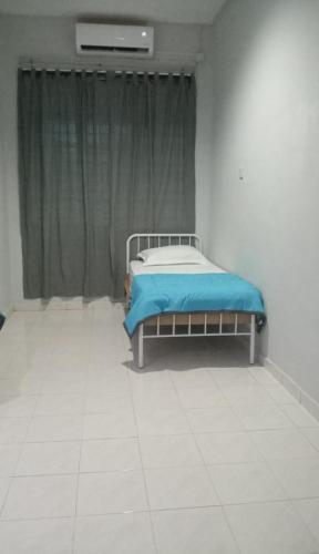 a bedroom with a bed with a blue blanket at Homestay Taman Delima Paka in Kampong Gong Gemia