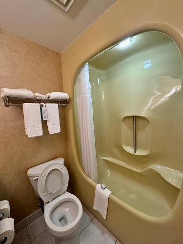 a bathroom with a toilet and a shower with towels at Travelodge by Wyndham Prince Albert in Prince Albert