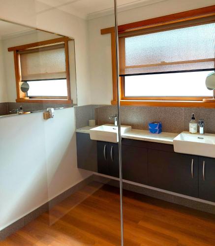 a bathroom with two sinks and two windows at Percy's Cottage in Devonport