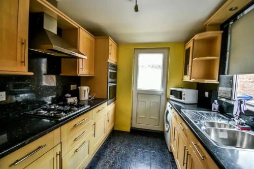 a kitchen with wooden cabinets and a sink and a window at Fitzwilliam House -3 Bedrooms - Sleeps 5 in Redcar