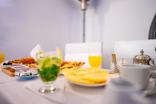 a table with a plate of food and glasses of orange juice at Riad L'ECOLE in Marrakech