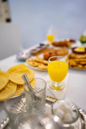 a table with a glass of orange juice and pancakes at Riad L'ECOLE in Marrakech