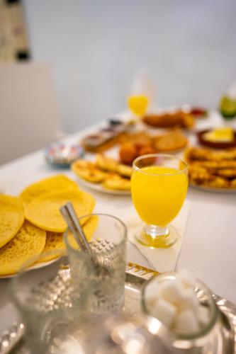 a table with a glass of orange juice and pancakes at Riad L'ECOLE in Marrakech
