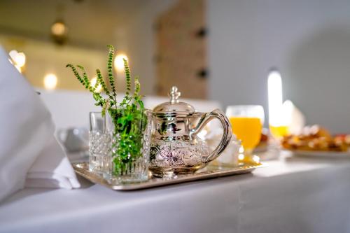 a table with a tray with a tea kettle and flowers at Riad L'ECOLE in Marrakech