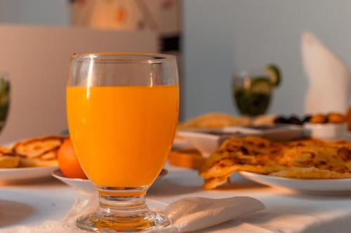 a glass of orange juice sitting on a table with food at Riad L'ECOLE in Marrakech