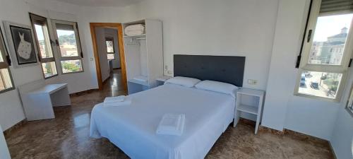 a bedroom with a white bed in a room with windows at Edificio Primavera Viviendas turísticas in Calasparra