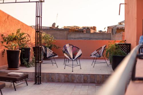 a group of chairs sitting on a rooftop patio at Riad L'ECOLE in Marrakech