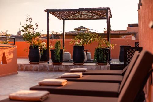 a row of benches on a rooftop with potted plants at Riad L'ECOLE in Marrakech