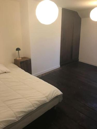 une chambre avec un lit et une lampe sur une table dans l'établissement Joli appart au cœur du village, à Castillon-en-Couserans