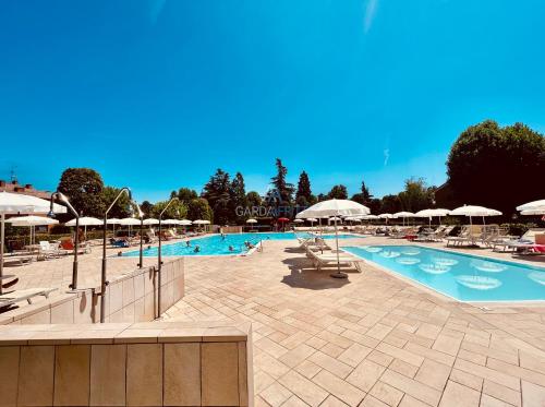 una grande piscina con sedie e ombrelloni di Flora Apt -100m dal Lago di Garda - Piscina a Sirmione
