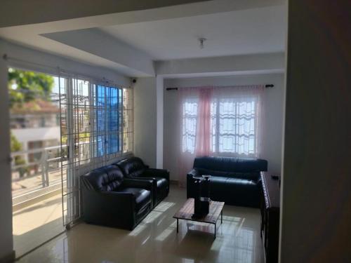 a living room with two black couches and large windows at Apartamentos Pinos del Rodadero in Santa Marta