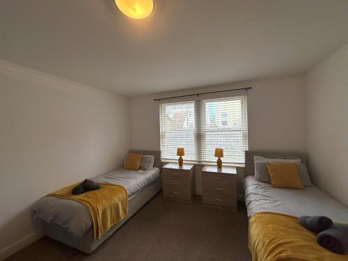 a bedroom with two beds and a window at Curwen Apartment - 2 Bedrooms - Sleeps 6 in Workington